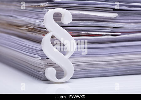 Close-up Of Red Paragraph Symbol Leaning On Documents