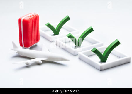 Miniature Red Bag And Plane With Checklist On White Backdrop Stock Photo