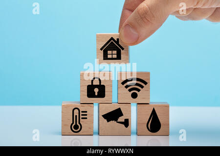 Hand Placing Wooden Block With Home Icon Over Stacked Home Automation Icons Wooden Block Stock Photo