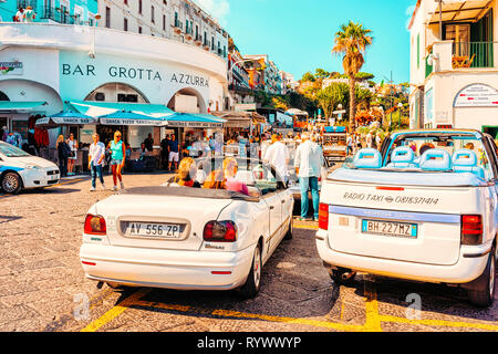 Capri, Italy - October 3, 2017: Street with taxi cars transport and tourists in Capri Island town in Italy at Naples. Cityscape with road and people, Italian coast. Anacapri in Europe. Amalfi, summer Stock Photo