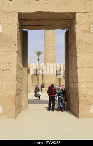 Family of visitors, woman in hijab, standing in a large stone entry way, Precinct of Amun-Re, Karnak Temple Complex, Luxor, Egypt Stock Photo