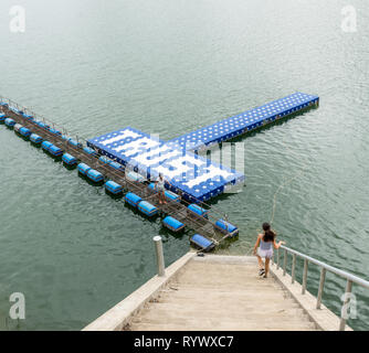 Teenager walking down stairs and mother standing on float at resevoir in Thailand Stock Photo