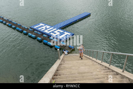 Teenager  running up stairs and mother sitting at bottom at resevoir in Thailand Stock Photo