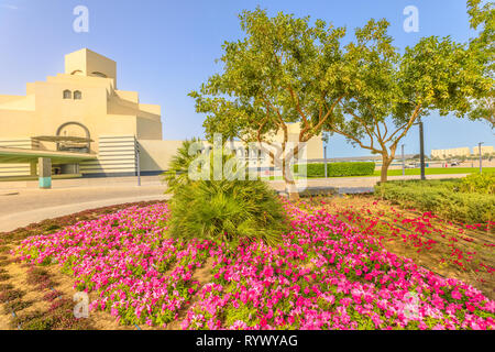 Flower beds and blooming trees along seafront of Doha Bay in Doha park. Popular tourist attraction near Corniche in city center. Qatar, Middle East Stock Photo