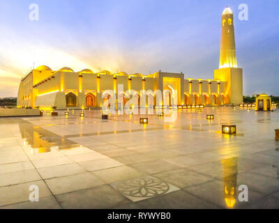Scenic Doha Grand Mosque with minaret illuminated, mirrors on the outdoor marble pavement. Qatar State Mosque, Middle East, Arabian Peninsula in Stock Photo