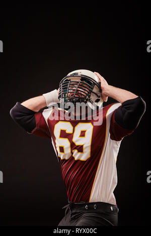Isolated American football player rejoices in victory in black background Stock Photo