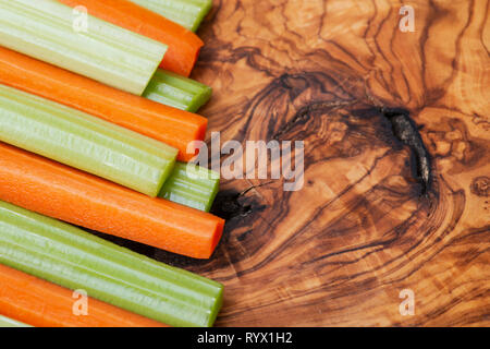 Raw peeled and cut Organic Celery Stalks and Orange Carrots arranged on natural olive wood. Apiaceae or Umbelliferae family. Delicious diet snack. Stock Photo