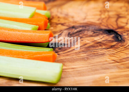 Raw peeled and cut Organic Celery Stalks and Orange Carrots arranged on natural olive wood. Apiaceae or Umbelliferae family. Delicious diet snack. Stock Photo