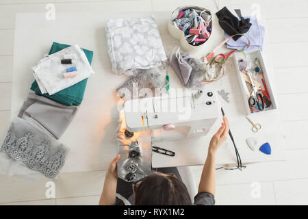 Tailor, fashion and seamstress concept - young female fashion designer in her showroom, top view. Stock Photo