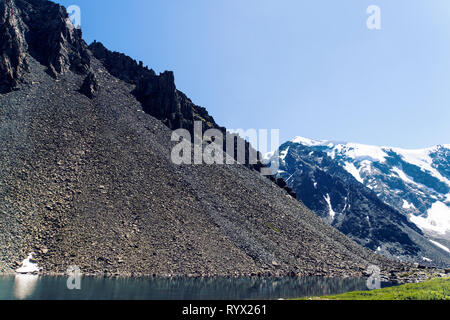 screes. Kurumnik is a pile of fragments of rocks. Scattering of large stones in the Altai mountains on the background of snowy peaks. Stock Photo