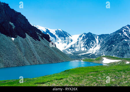 Beautiful view of idyllic colorful summer scenery with mountain summit reflecting in crystal clear mountain lake in summer. green meadow with fresh gr Stock Photo