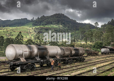 A couple walk along the tracks at Nanu-Oya Station, as storm c;louds gather over the hills in the Central Province of Sri Lanka, using the railway lin Stock Photo