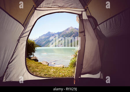 View from inside to outside Yellow tent. A lake view. Camping in the woods. Mountain lake Kucherlinskoe from above, Altay, Russia. Stock Photo
