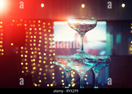 Top tiers of champagne tower at the illumination and projector screen background of wedding banquet hall. Beautifull set of coupe glasses at at the lo Stock Photo