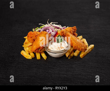Crispy chicken wings with french fries on black slate background Stock Photo