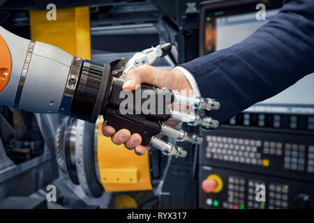 Hand of a businessman shaking hands with a Android robot. The concept of human interaction with artificial intelligence. Stock Photo