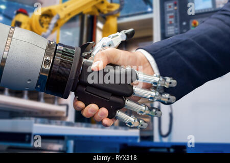 Hand of a businessman shaking hands with a Android robot. The concept of human interaction with artificial intelligence. Stock Photo