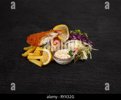 Schnitzel with fries and fresh salad and sauce on black background Stock Photo