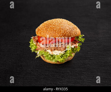Pulled pork burger with fresh salad and tomato on dark background Stock Photo