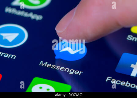 Finger pressing the Facebook Messenger app icon on a tablet or mobile phone touchscreen. Facebook Messenger shortcut. Stock Photo