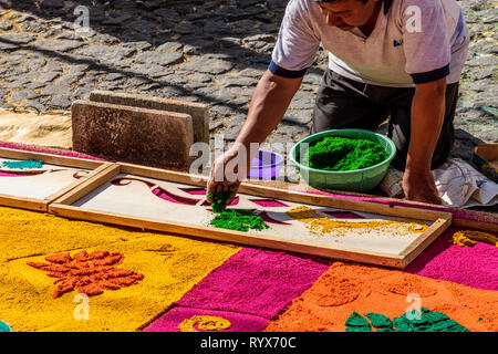 Antigua, Guatemala -  March 11, 2018: Decorating dyed sawdust Lent carpet destroyed moments later by passing processions in colonial town. Stock Photo