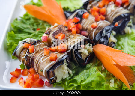 eggplant rolls with nuts on a white plate Stock Photo