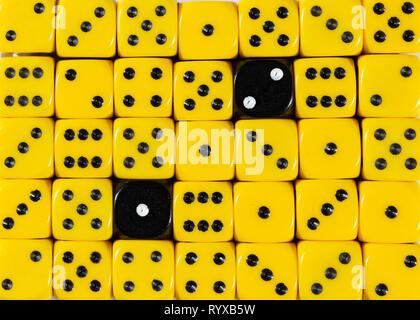 Background of random ordered yellow dices with two black cubes Stock Photo