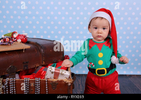 A small boy dressed up as an elf stands in Christmas decorations. Stock Photo