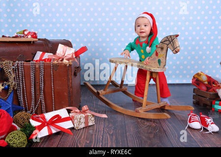 A small boy dressed up as an elf stands in Christmas decorations. Stock Photo