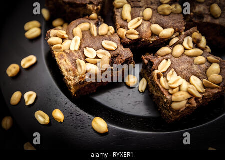 Homemade brownies with peanuts on a dark brown plade. Original recipe from usa Stock Photo