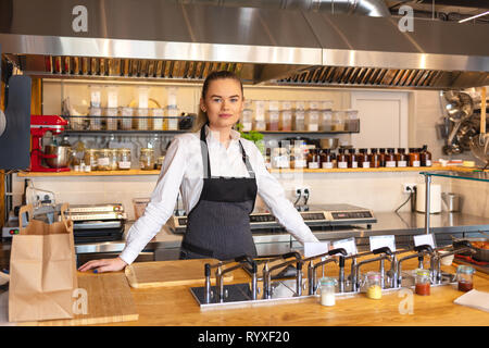 Successful owner standing behind counter in small eatery restaurant Stock Photo