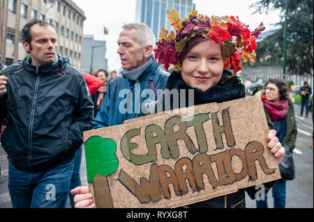 A woman is seen holding a placard that says Earth warrior during the Global climate strike for future rally. This Friday, tens of thousands of kids in more of 60 countries went on strike to demand climate change action. The school strike movement was inspired by Swedish teenager Greta Thunberg, who has been striking from school every Friday since last August to stand outside the Swedish parliament building and demand that her home country adheres to the Paris agreement on climate change. In Brussels, not just students, but teachers, scientists, and several syndicates took the streets of the Be Stock Photo