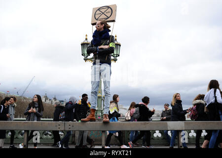 London, UK. 15th Mar, 2019. A member of the climate activist group Extinction Rebellion seen standing on Westminster Bridge during the protest.Protest against climate change during the youth strike climate protest winds down. The event followed similar 'strikes' held last month, in London and across the country, and forms part of a burgeoning global movement of young people taking direct action to call attention to the threats posed by global warming for the future of the planet. Credit: David Cliff/SOPA Images/ZUMA Wire/Alamy Live News Stock Photo