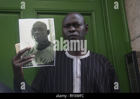 Madrid, Spain. 15th Mar, 2019. Man carries the photo of Mame Mbaye in the portal where he died.Protest against institutional racism took place at Nelson Mandela square one year after the death of Mame Mbaye, a Senegalese street vendor who died while being chased by the police for selling on the streets. According to the demonstrators, the young man did not have any legal papers despite having spent more than 10 years in Spain and authorities did not help his family after his death. Credit: Lito Lizana/SOPA Images/ZUMA Wire/Alamy Live News Stock Photo