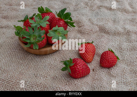 Ripe strawberries in a wooden bowl, and on sack surface Stock Photo