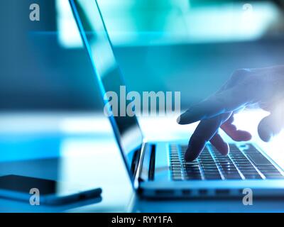 Man typing on a laptop computer at his desk. Stock Photo
