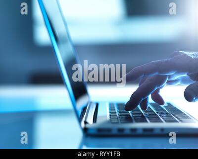 Man typing on a laptop computer at his desk. Stock Photo