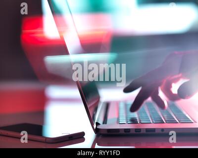 Man typing on a laptop computer at his desk. Stock Photo
