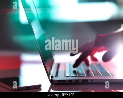 Man typing on a laptop computer at his desk. Stock Photo