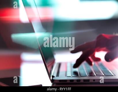 Man typing on a laptop computer at his desk. Stock Photo