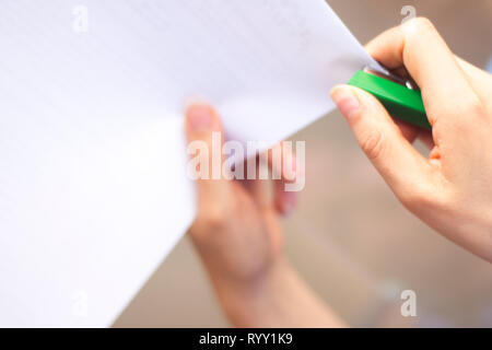 Office staple gun stapling paper in hand of young lady. Stock Photo