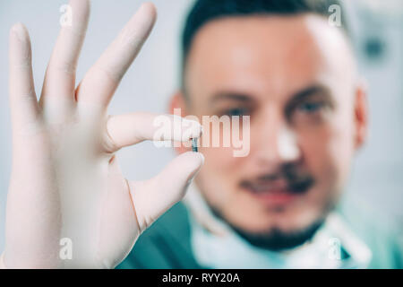 Dentist holding dental implant. Stock Photo