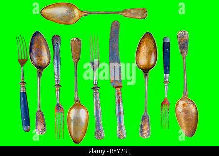 Vintage cutlery on a green background. Top view. Crazy concept for culinary and modern life. Contrast between shabby cutlery and excellent modern colo Stock Photo