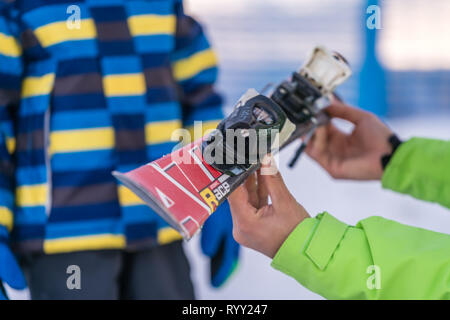 Szklarska Poreba, Poland - February 2019 : Ski instructor holding little boy skis and explaining him the safety features of equipment Stock Photo