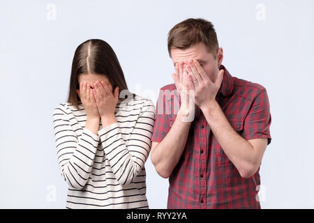 Portrait of a young european couple covering face with hands Stock Photo