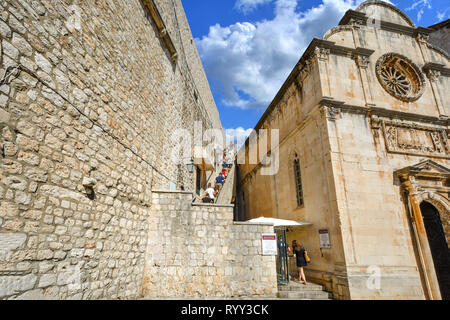 Tourists climb the staircase to the ancient city walls of Dubrovnik near Saint Saviour Church on the Dalmation coast of Croatia on a sunny summer day Stock Photo