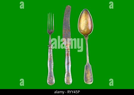 Vintage cutlery on a green background. Top view. Crazy concept for culinary and modern life. Contrast between shabby cutlery and excellent modern colo Stock Photo