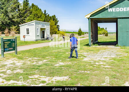 WEDDERBURN NEW ZEALAND - OCTOBER 22 2018; tourists and cysclists at Wedderburn on Central Otago Rail Trail old landmark green rail shed Stock Photo