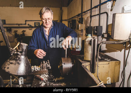 An skilled engineer tightening up a chuck on a lathe in an engineering factory in Kent, UK Stock Photo