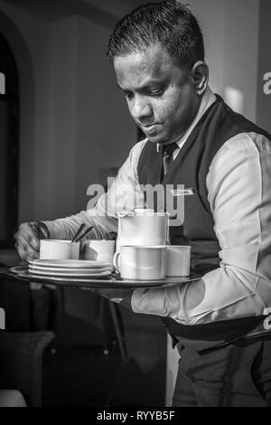 Suhith - A professional Waiter at the historic Galle Face hotel in Colombo Sri Lanka, dispensing tea to the guests on the seafront patio. Stock Photo